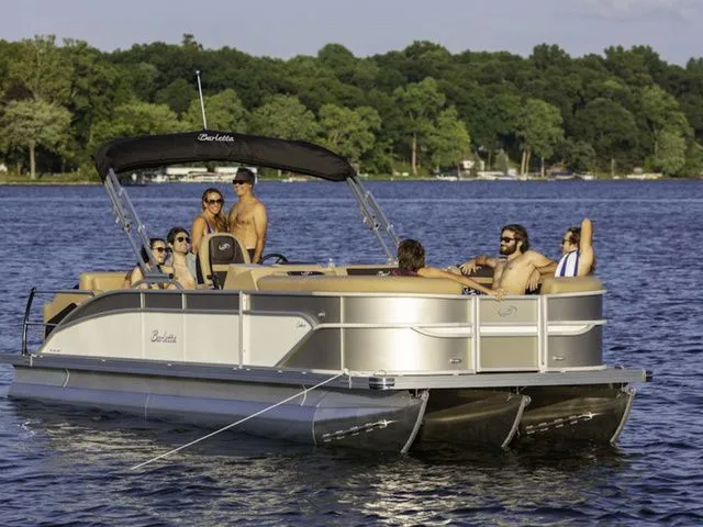 The Image of 2025 Barletta C24UE pontoon boat on a lake with passengers enjoying the sun. - 1