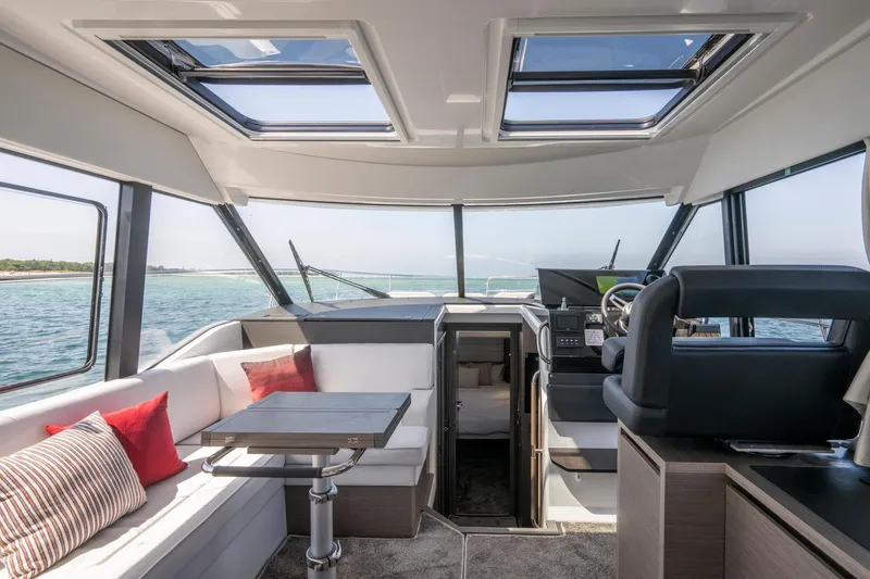 Slide: The Image of Interior of 2026 Jeanneau NC1295 Coupe yacht with panoramic windows and modern seating. - 19