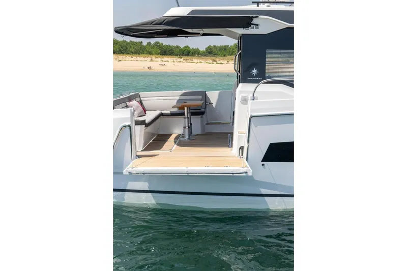 Slide: The Image of 2026 Jeanneau NC1295 Coupe boat with open deck, near sandy beach. - 5
