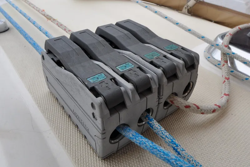 Slide: The Image of Rope clutches on a 2004 Sabre 426 sailboat deck, securing blue and white ropes. - 11