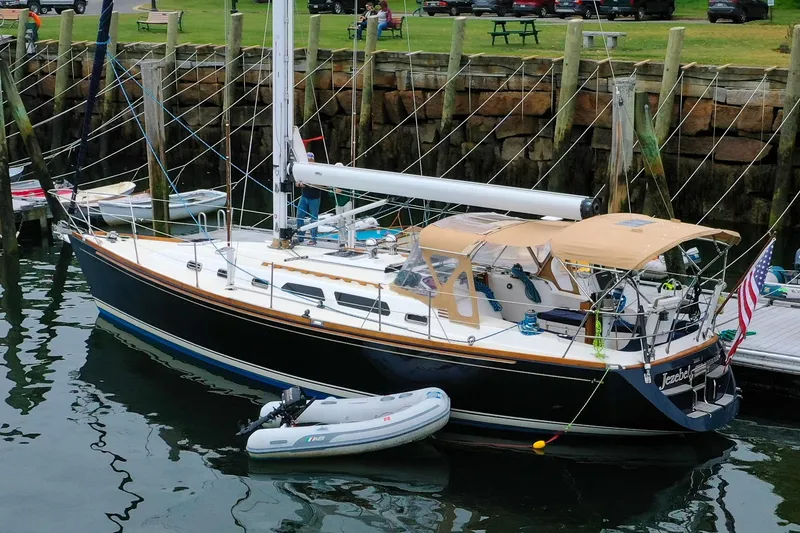 Slide: The Image of 2004 Sabre 426 sailboat docked with inflatable dinghy, American flag displayed. - 2