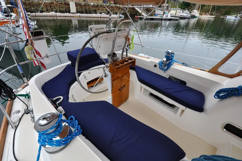 Slide: The Image of 2004 Sabre 426 sailboat cockpit with blue cushions and steering wheel, docked in a marina. - 26