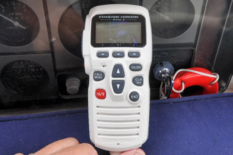 Slide: The Image of Hand holding Standard Horizon RAM3 marine radio on Sabre 426, 2004 model dashboard. - 30