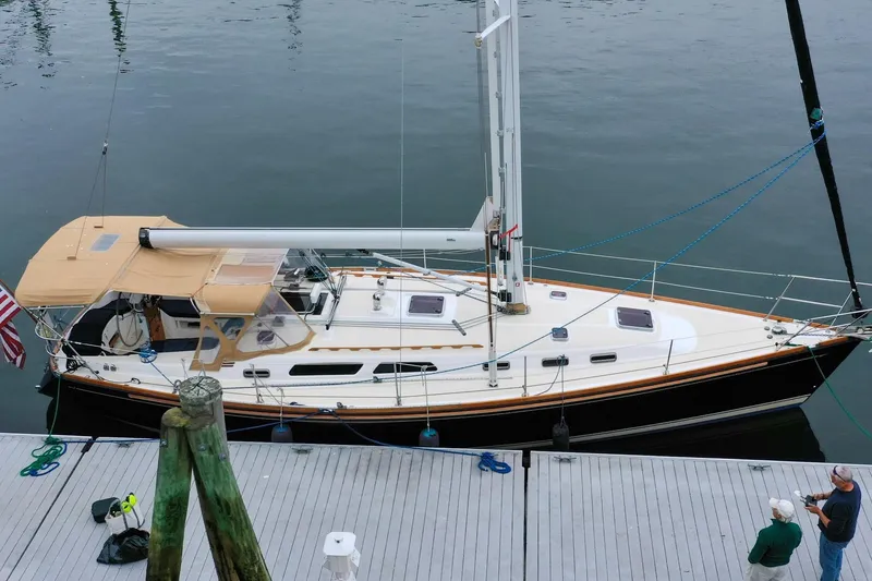 Slide: The Image of 2004 Sabre 426 sailboat docked, featuring tan canopy and sleek design. - 4