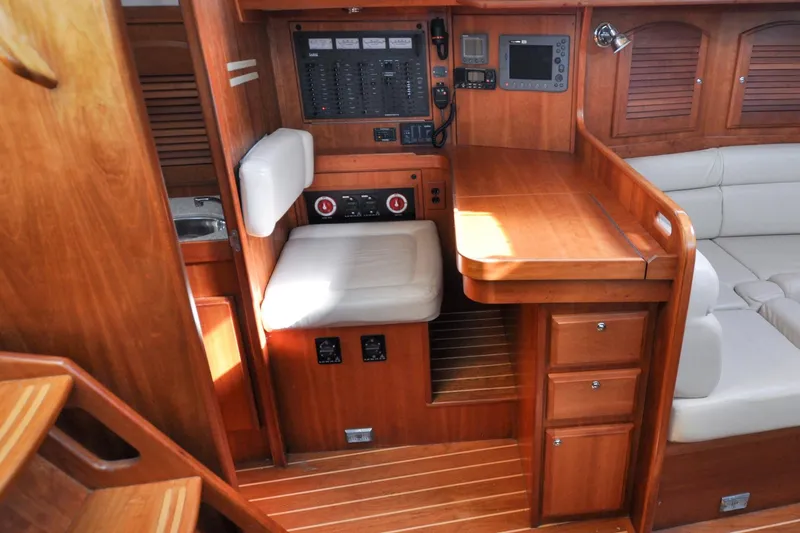 Slide: The Image of 2004 Sabre 426 yacht interior with wooden cabinetry, navigation station, and cushioned seating. - 95
