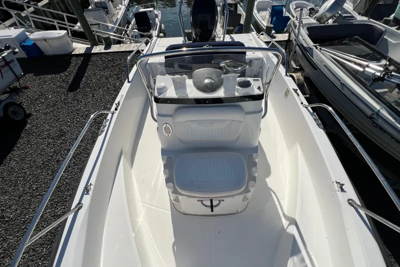 Slide: The Image of 2009 Boston Whaler 180 Dauntless boat interior, featuring helm and seating, docked at marina. - 12