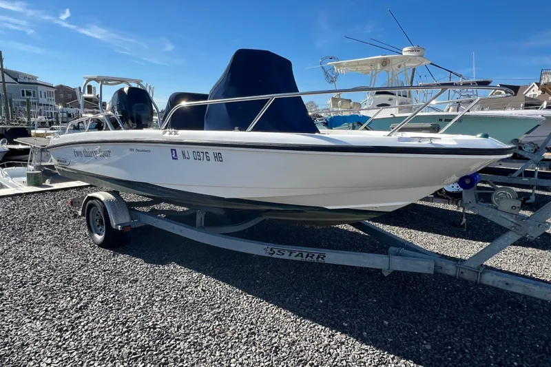 Slide: The Image of 2009 Boston Whaler 180 Dauntless boat on trailer, parked on gravel lot. - 4