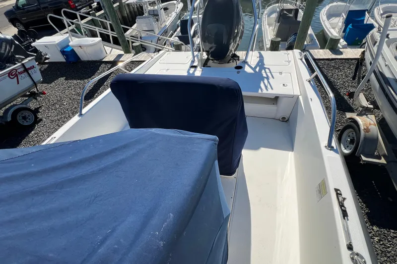 Slide: The Image of 2009 Boston Whaler 180 Dauntless boat interior with blue covers, docked among other boats. - 8