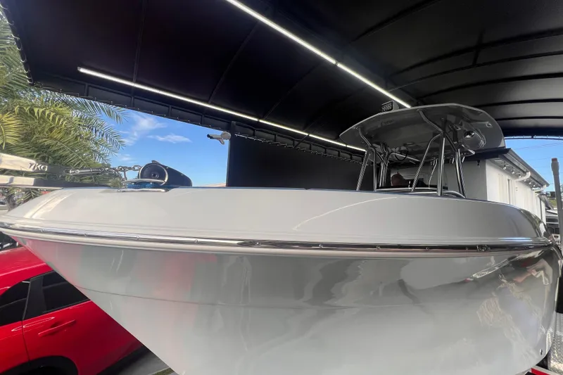 Slide: The Image of 2022 Aquasport 2300 Center Console boat under a canopy, with palm trees in the background. - 2
