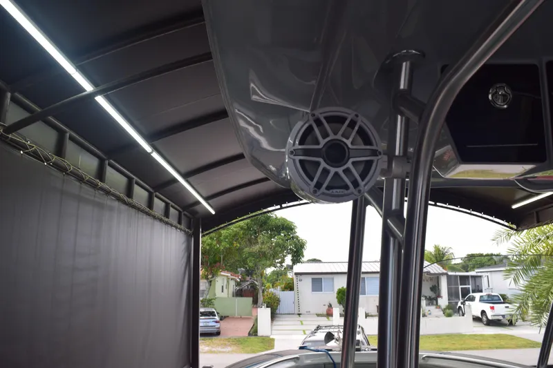 Slide: The Image of 2022 Aquasport 2300 Center Console boat under a covered structure with visible speaker. - 36