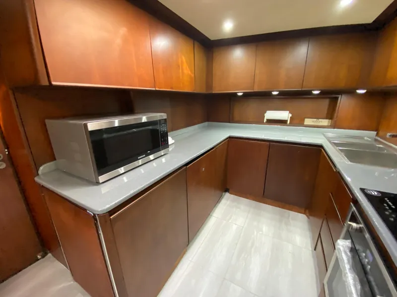 Slide: The Image of Modern kitchen with wooden cabinets, microwave, and sleek countertops in a 2007 Rodriquez 80 Widebody yacht. - 35