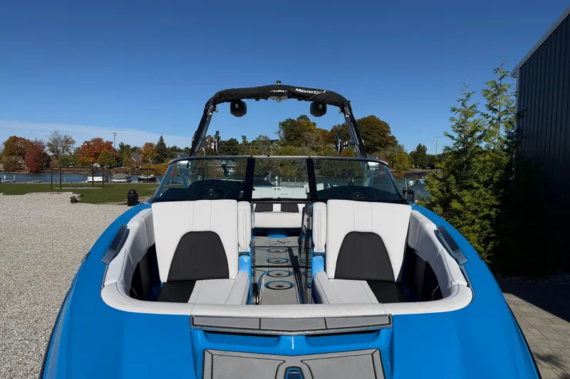 Slide: The Image of 2019 MasterCraft X24 boat with blue exterior and white seating, parked outdoors. - 4