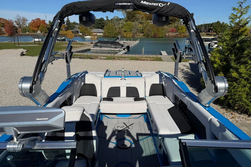 Slide: The Image of 2019 MasterCraft X24 boat interior with plush seating, docked by a scenic lake. - 5