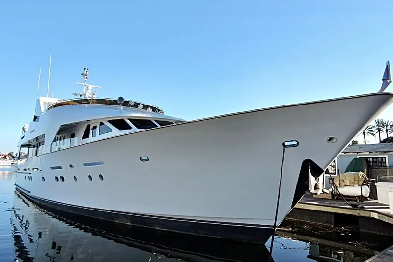 Slide: The Image of Luxurious 1992 Christensen motor yacht docked, reflecting on calm water, surrounded by palm trees. - 4