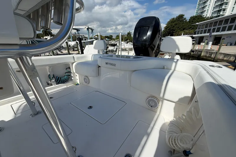 Slide: The Image of 2016 Contender 24 Sport boat interior with seating and storage, docked under a cloudy sky. - 10