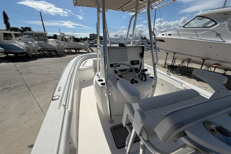 Slide: The Image of 2016 Contender 24 Sport boat interior with steering console, docked among other boats. - 12