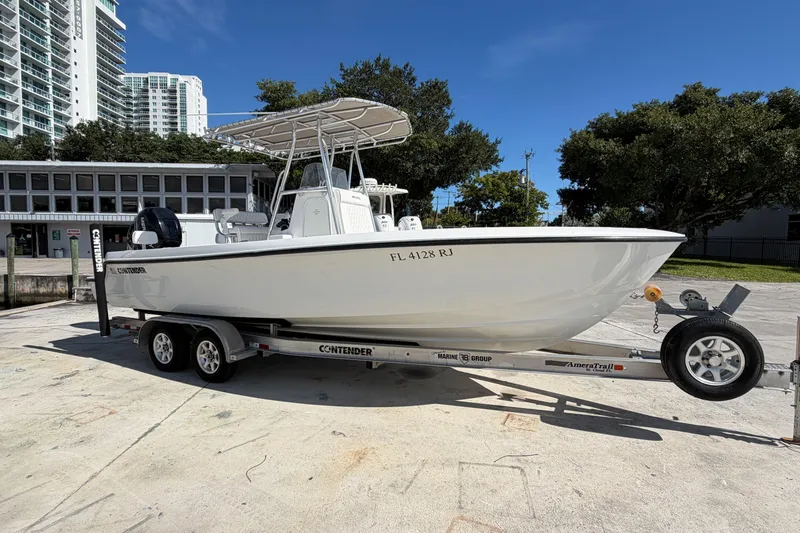 The Image of 2016 Contender 24 Sport boat on trailer, parked outdoors under clear blue sky. - 2