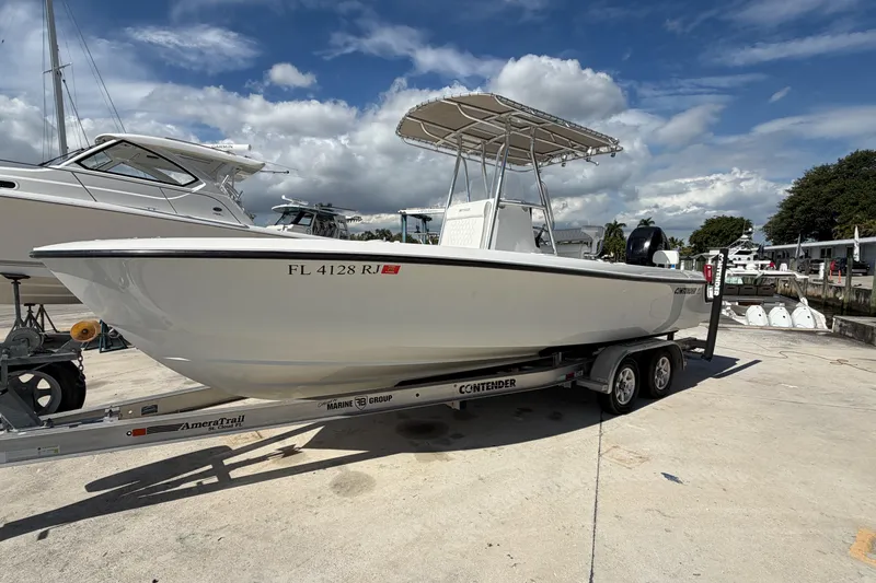 Slide: The Image of 2016 Contender 24 Sport boat on trailer, parked at marina under blue sky. - 4