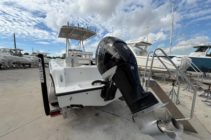 Slide: The Image of 2016 Contender 24 Sport boat with powerful outboard motor, docked under a partly cloudy sky. - 6