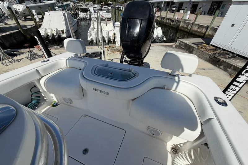 Slide: The Image of 2016 Contender 24 Sport boat interior with seating and motor at a marina. - 9