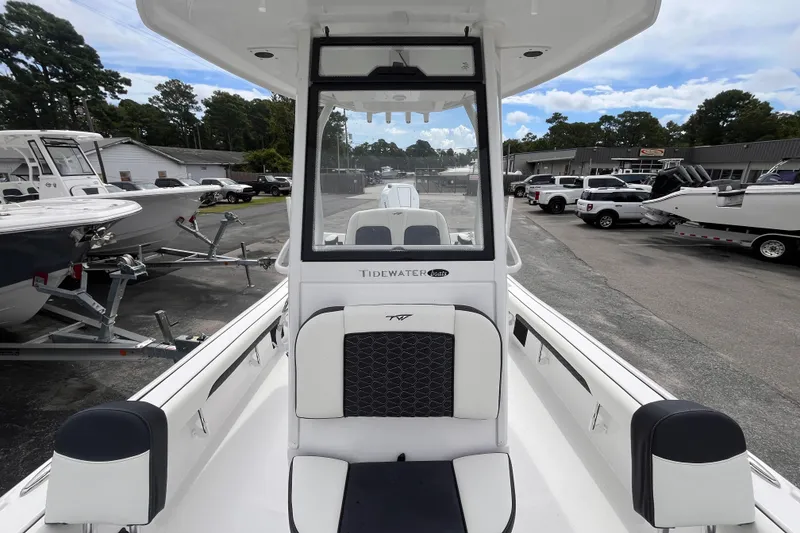 Slide: The Image of 2026 Tidewater 2500 Carolina Bay boat interior with seating and console, parked outdoors. - 13