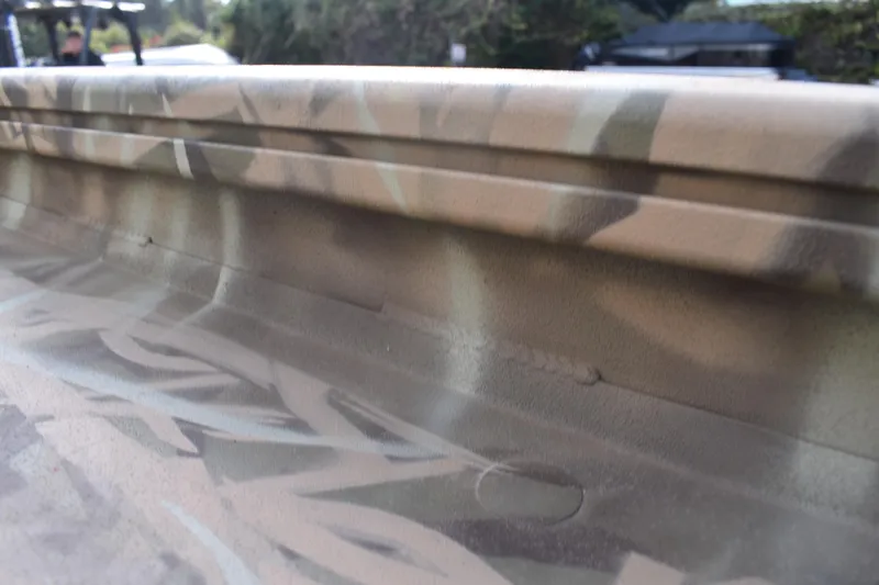 Slide: The Image of Camouflage-patterned side of a 2026 Lowe Roughneck RX1860 Tunnel Jet boat. - 13