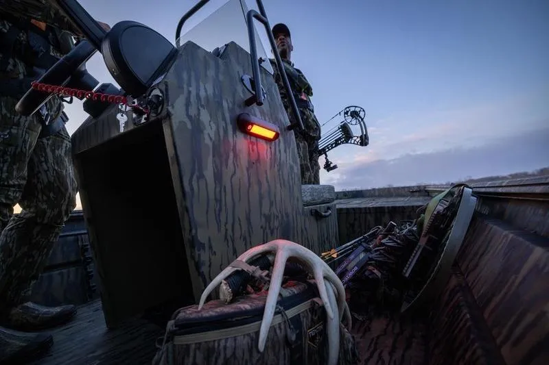 Slide: The Image of 2026 Lowe Roughneck RX1860 Tunnel Jet boat with camo pattern and storage compartments. - 7