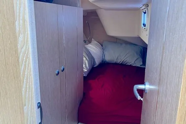 Slide: The Image of Cozy cabin interior of 2017 Hanse 315 sailboat with red bedding and wooden cabinetry. - 31