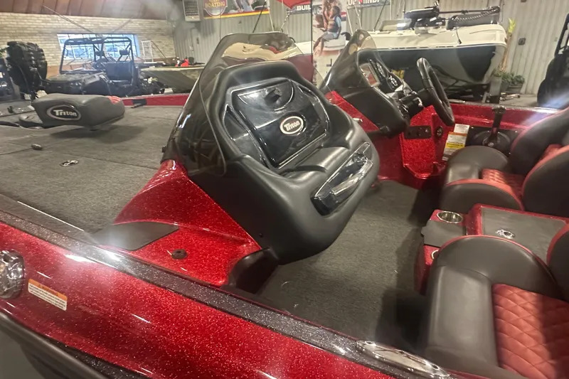 Slide: The Image of 2019 Triton 18 TrX boat interior with red and black seating, steering console, and carpeted deck. - 10