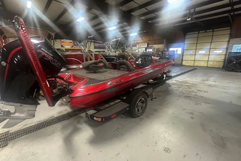 Slide: The Image of 2019 Triton 18 TrX bass boat in a showroom, featuring a sleek red design. - 2