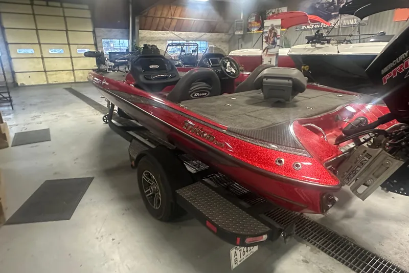 Slide: The Image of 2019 Triton 18 TrX bass boat in showroom, featuring sleek red design and modern equipment. - 4