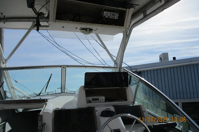 Slide: The Image of 1996 Grady-White Sailfish 272 boat cockpit with steering wheel and electronics under a clear sky. - 8