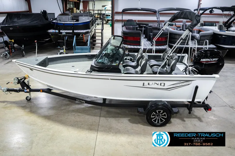 The Image of 2026 Lund 1700 Explorer Sport boat in showroom, featuring Mercury engine and trailer. - 2