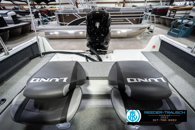 Slide: The Image of 2026 Lund 1700 Explorer Sport boat interior with dual seats and motor in showroom. - 22