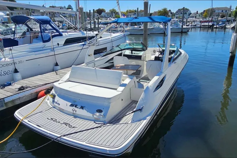 Slide: The Image of 2016 Sea Ray 230 SLX boat docked in a marina, featuring sleek design and spacious seating. - 13