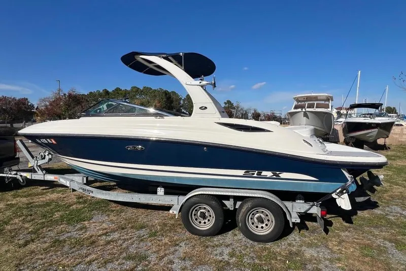Slide: The Image of 2016 Sea Ray 230 SLX boat on trailer, parked outdoors under clear blue sky. - 24