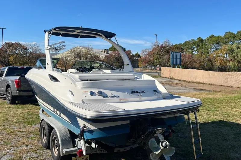 Slide: The Image of 2016 Sea Ray 230 SLX boat on trailer, parked outdoors on a sunny day. - 25