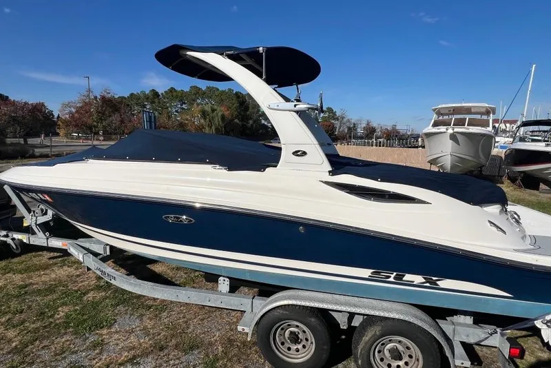 Slide: The Image of 2016 Sea Ray 230 SLX boat on trailer, blue and white design, parked outdoors. - 28