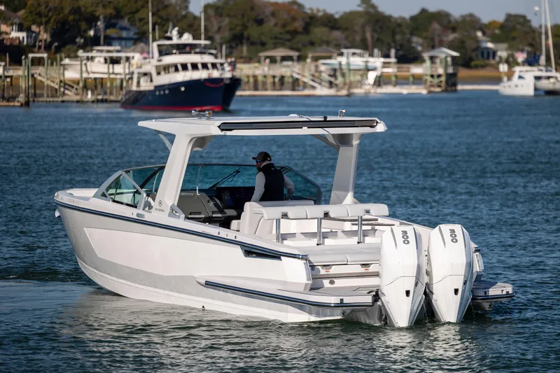 Slide: The Image of 2023 Aviara AV32 OB boat cruising on a calm waterway with scenic background. - 2