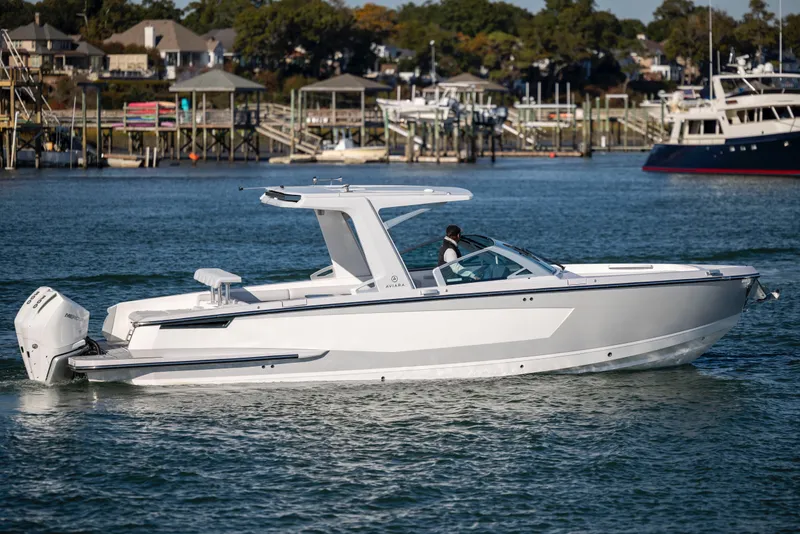 Slide: The Image of 2023 Aviara AV32 OB boat cruising on a scenic waterfront with docks in the background. - 4
