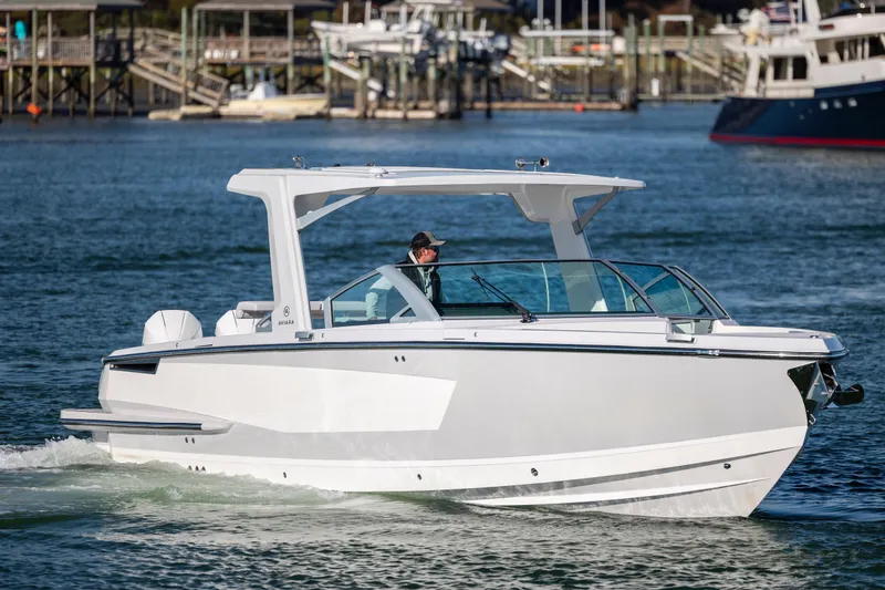 Slide: The Image of 2023 Aviara AV32 OB boat cruising on a calm waterway with docks in the background. - 5