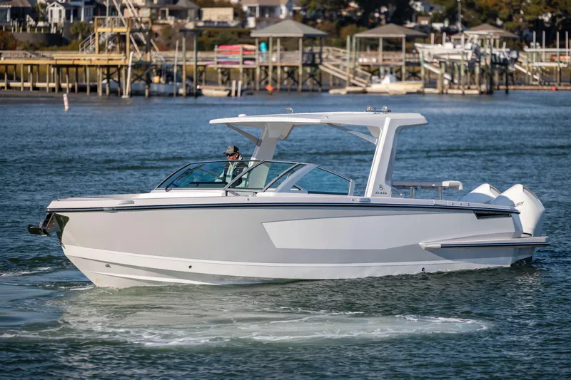 Slide: The Image of 2023 Aviara AV32 OB boat cruising on a calm waterfront with docks in the background. - 7