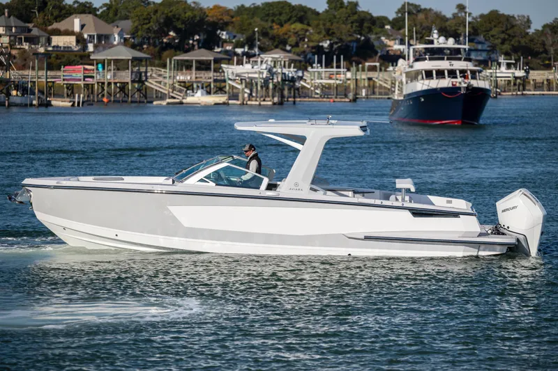 Slide: The Image of 2023 Aviara AV32 OB boat cruising on a scenic waterfront with docks and trees. - 8