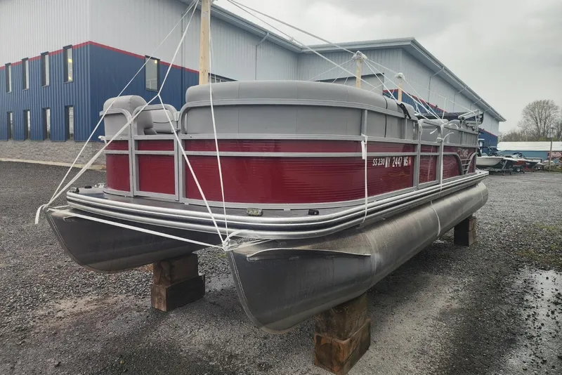 Slide: The Image of 2021 Lowe SS 230 WT pontoon boat docked with cover, surrounded by greenery. - 0