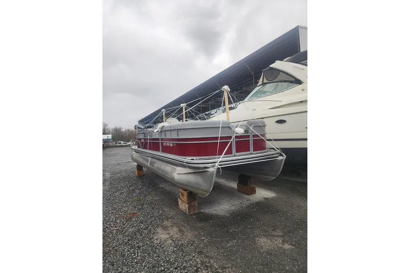 Slide: The Image of Pontoon boat and jet ski docked on a sunny lake, featuring a 2021 Lowe SS 230 WT. - 2