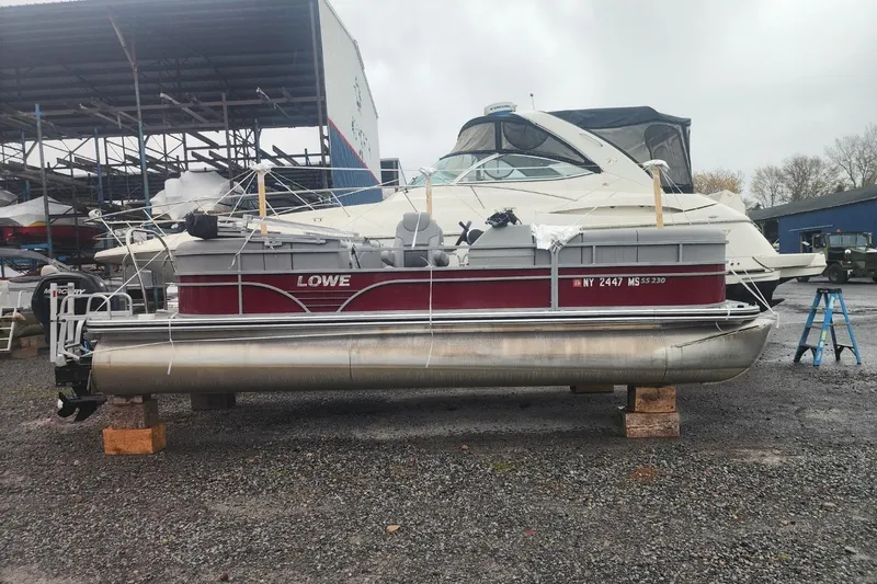 Slide: The Image of 2021 Lowe SS 230 WT pontoon boat on blocks, overcast sky. - 5