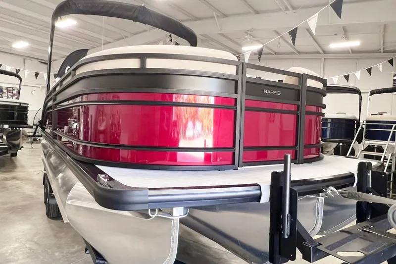 Slide: The Image of 2025 Harris Solstice 250 pontoon boat in showroom, featuring sleek red design. - 2