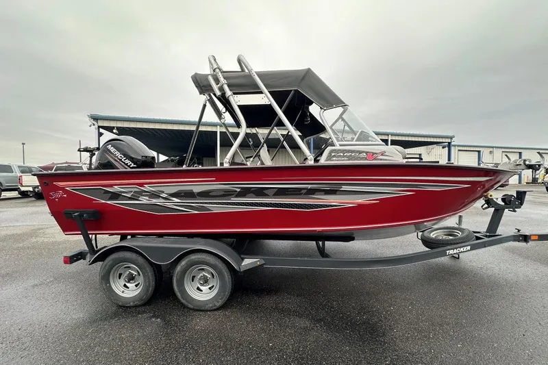 The Image of 2019 Tracker Targa V-19 Combo boat on trailer, red with black graphics, parked outdoors. - 0