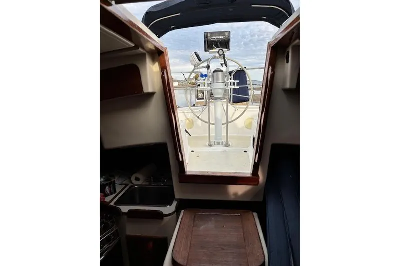 Slide: The Image of Interior view of 1988 Tartan 31 Cutter Rigged Masthead Sloop, showcasing helm and cabin entrance. - 21