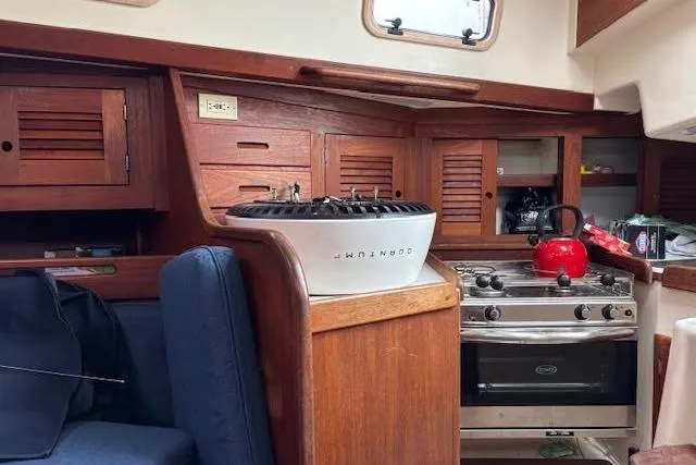 Slide: The Image of Interior of 1988 Tartan 31 Cutter Rigged Masthead Sloop with wooden cabinetry and kitchen area. - 32